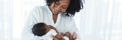 Mom holding baby and smiling at her. 