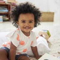 Portrait Of Happy Baby Girl Playing With Toys In Playroom 