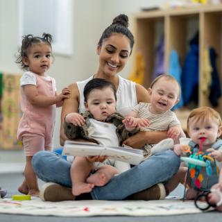 Child care provider reading to four toddlers.