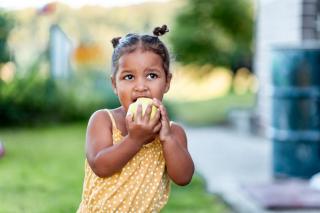 Little girl eating an apple. 