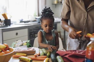 Preschool child helping mom make a healthy dinner. 