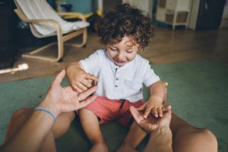 Toddler taking his teacher's hands.