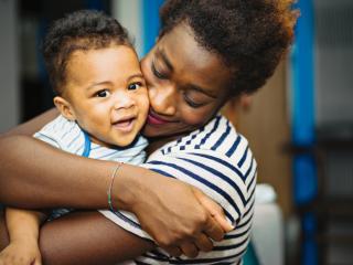 Adult hugging a happy toddler. 