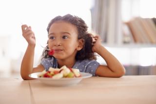 Little girl eating a fresh fruit salad. 