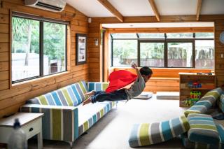 Little boy Supermaning onto a pile of cushions 