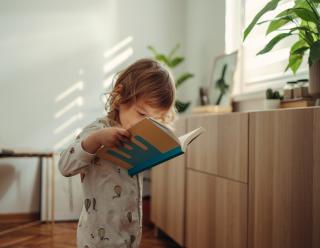 Toddler girl reading abook.