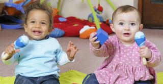 Two babies enjoying themselves playing music. 