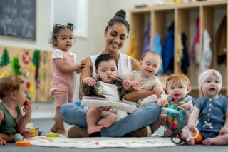 Child care provider reading to four toddlers.