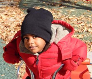 Young boy bundled up on bicycle 