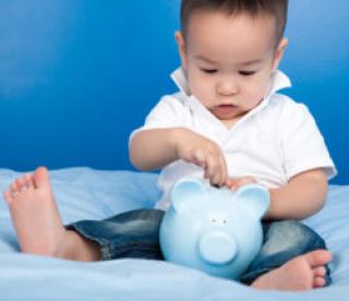 Boy putting money in blue piggy bank 