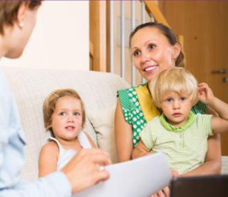 Home visitor interacting with happy mother with two children 