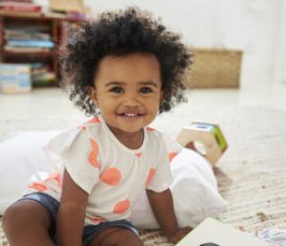 Portrait Of Happy Baby Girl Playing With Toys In Playroom 