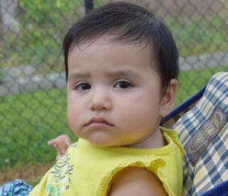 somber looking baby sitting in a stroller 