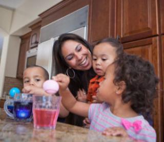 young family coloring easter eggs in kitchen 