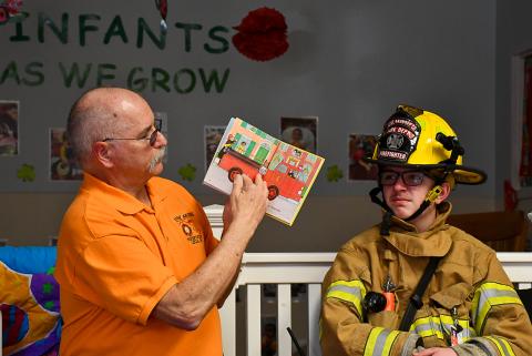 Fire fighter reading to kids.